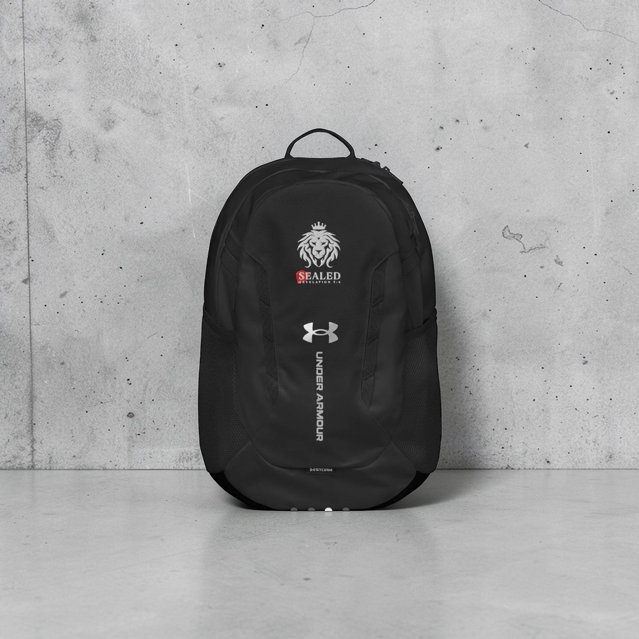Black and gray Under Armour backpack featuring Sealed Ministries lion logo and Revelation 7:4 design
